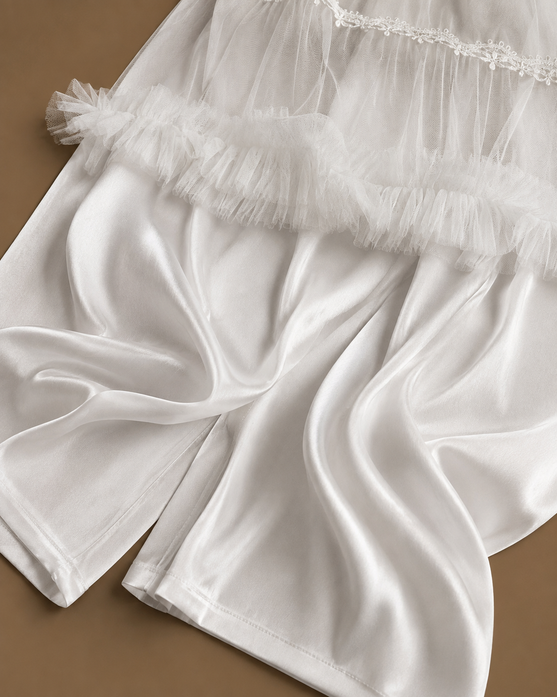 Fabric detail of the CHAIMAE bridal lounge set showing smooth ivory satin, sheer tulle and ruffled trim